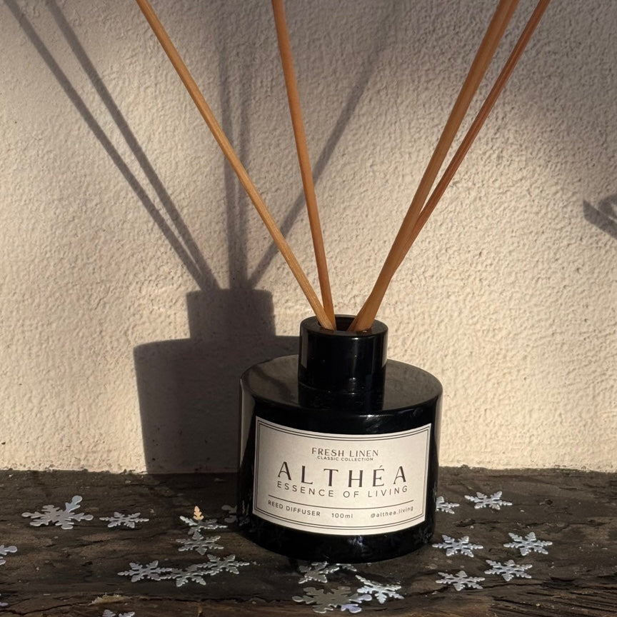 Reed diffuser with wooden sticks in a black container on a textured surface