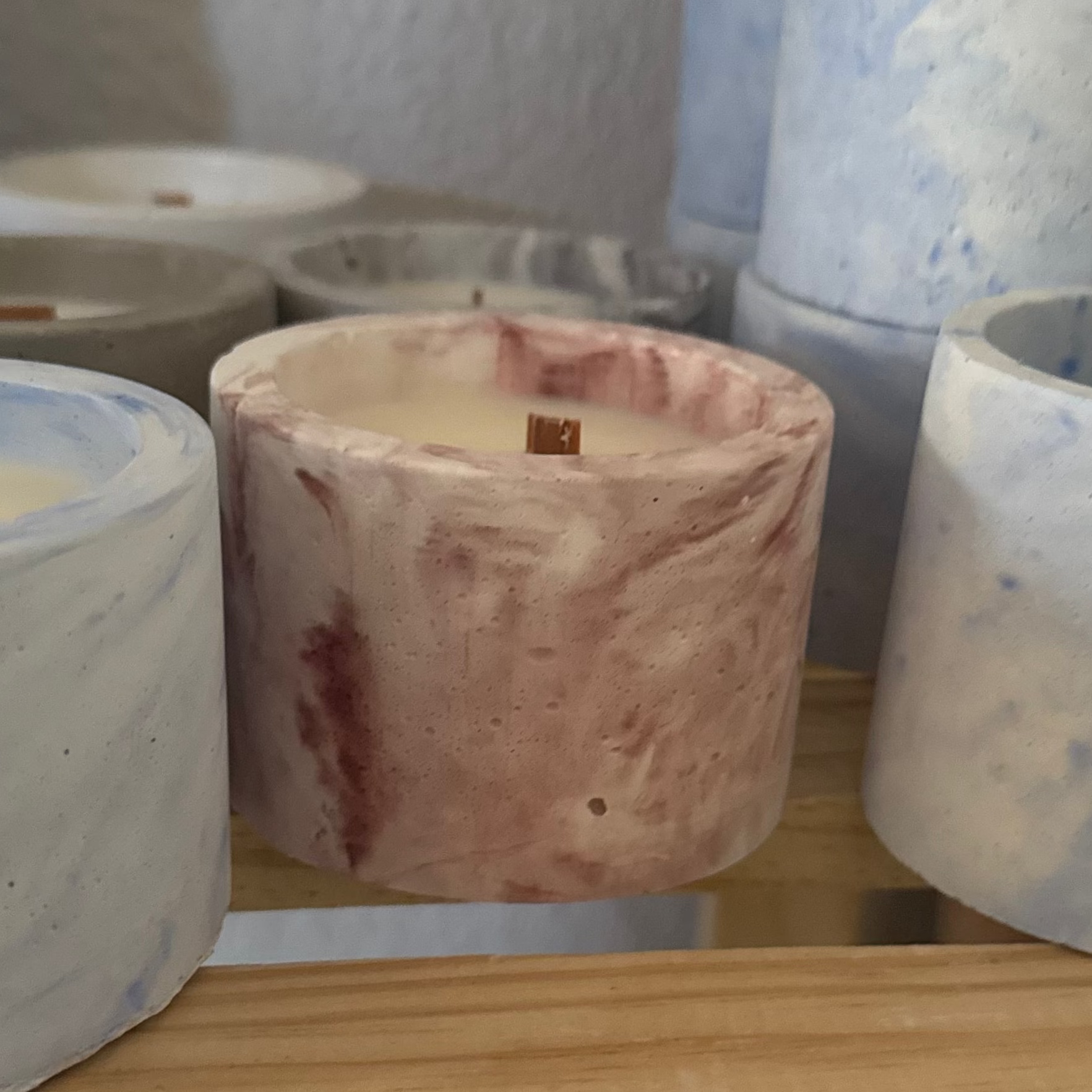 Decorative ceramic pots with marbled patterns on a wooden shelf.