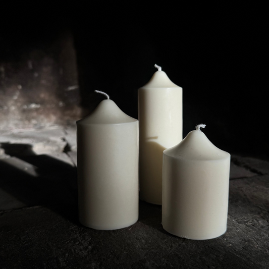Three white candles on a dark surface with a dark background