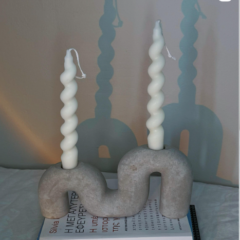 Decorative candle holders with twisted candles on a plain background