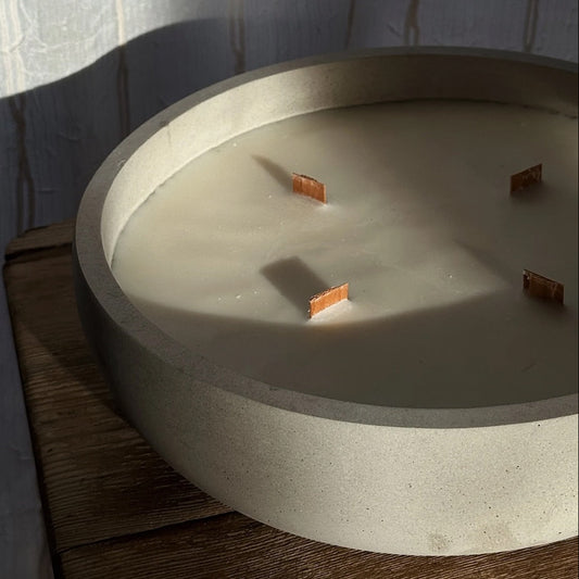 Concrete candle bowl with wooden wicks on a wooden surface