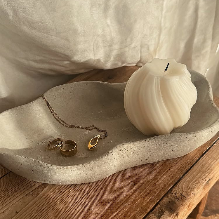Ceramic dish with a candle and jewelry on a wooden surface