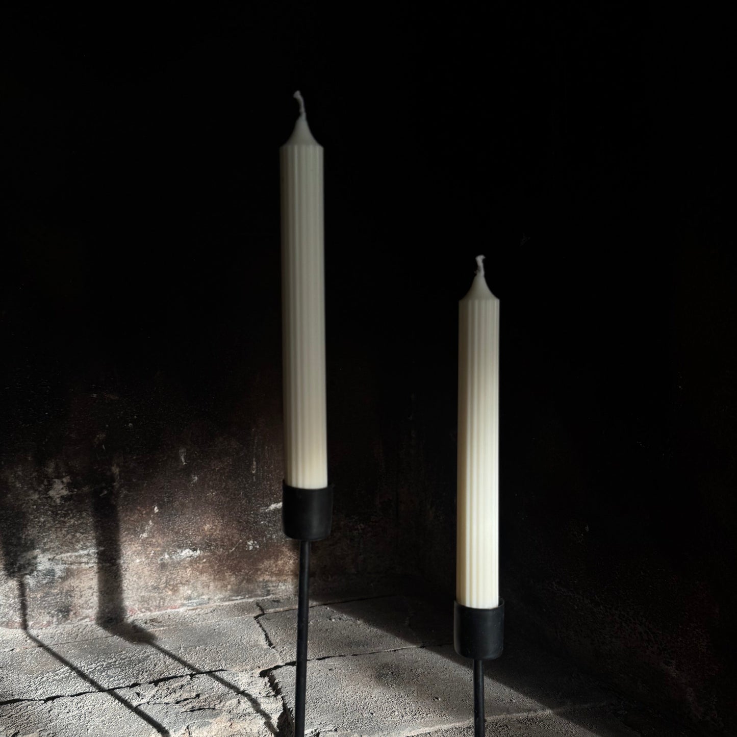 Two candles on stands against a dark background