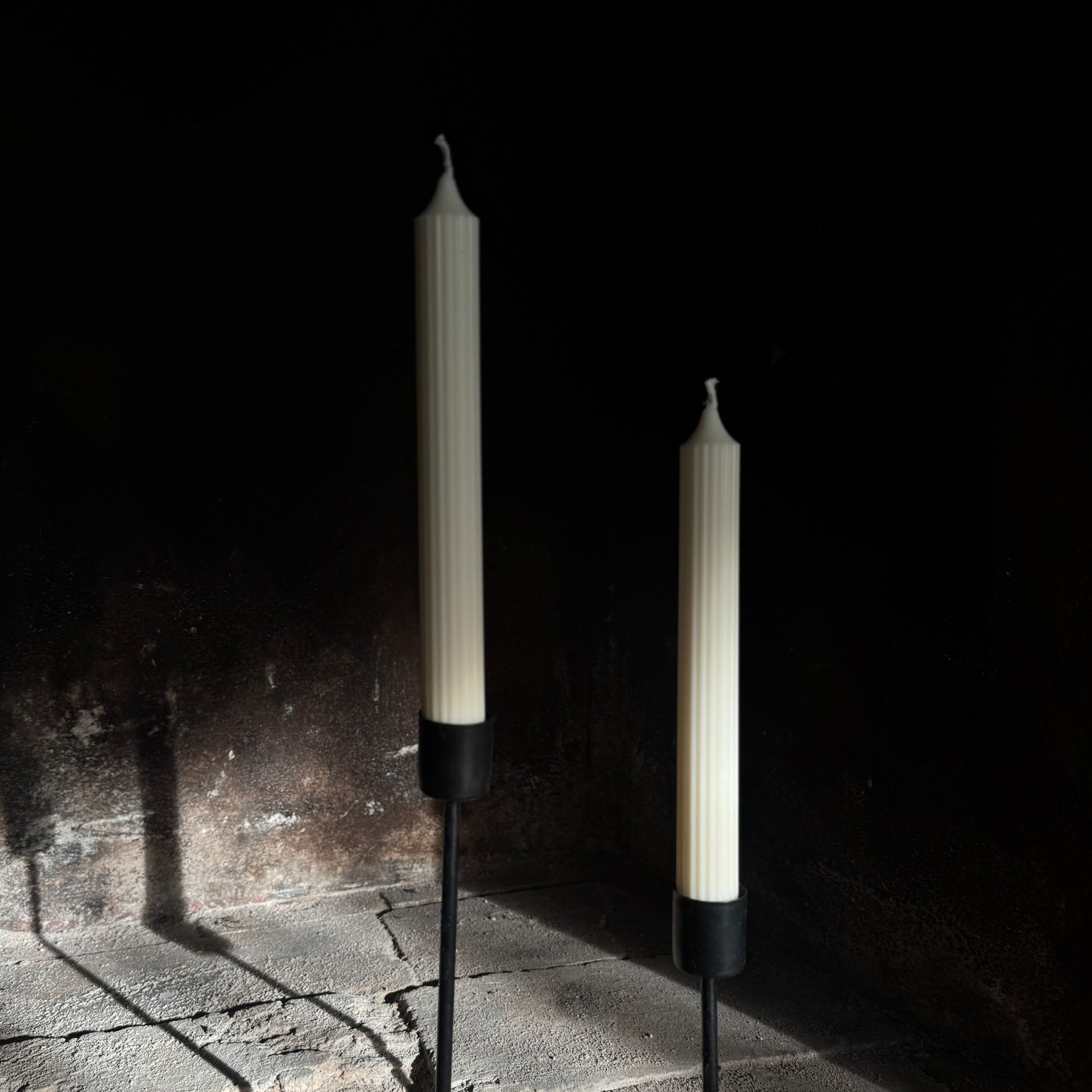 Two candles on stands against a dark background