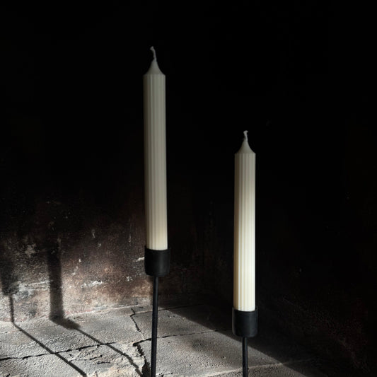 Two candles on stands against a dark background